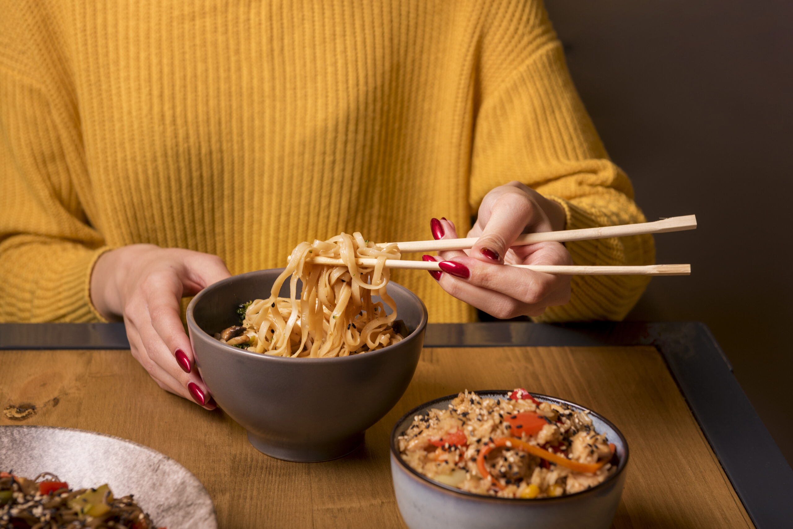 A woman eating noodles with chopsticks