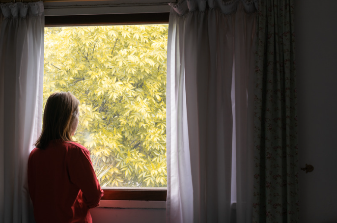 Woman looking out from room window