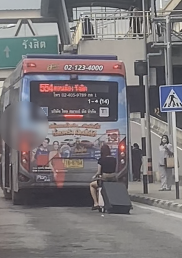 Woman riding motorised luggage behind a bus