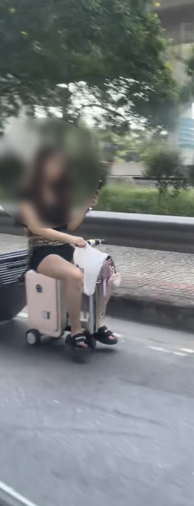 Woman riding motorised luggage