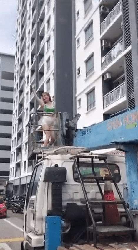 Woman standing on the crane waving to the camera